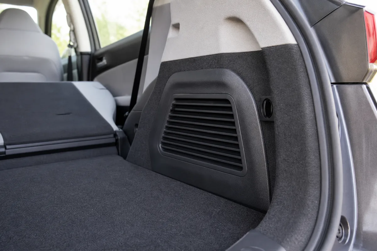 Banquette arrière rabattue d’une voiture révélant la grille d’aération latérale du coffre